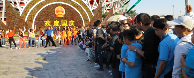 CATBIRD SEAT: Appell and his Gangnam-esque dancers attract an audience while videotaping outside Beijing’s Bird’s Nest Olympic stadium.